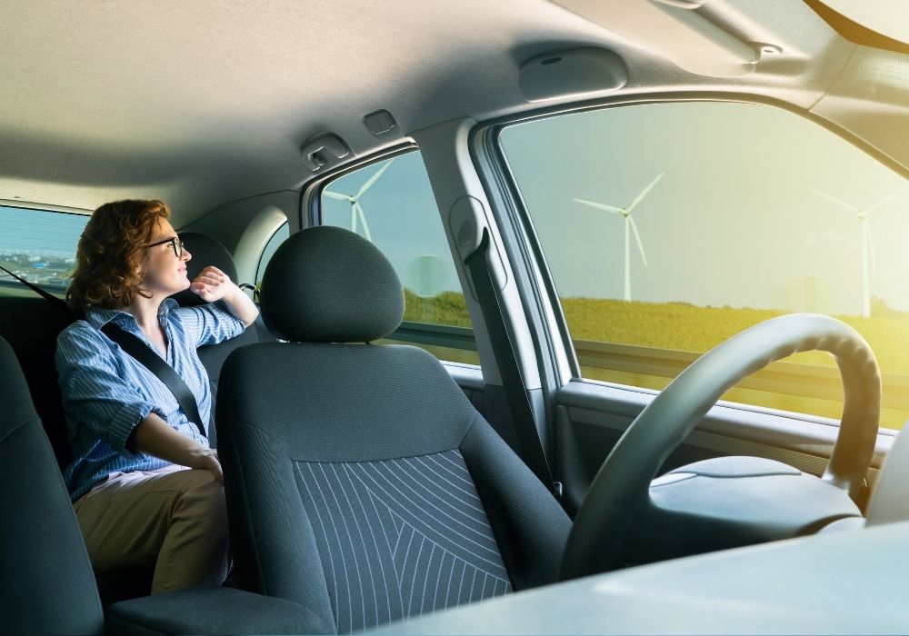 Lady sitting in the back of an autonomous vehicle.